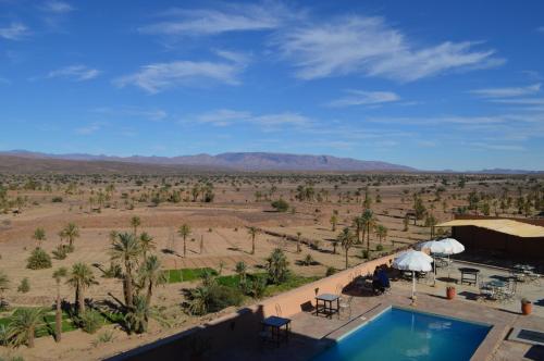 a resort with a swimming pool and a view of the desert at Hotel Kasbah Ennakhile in Nkob