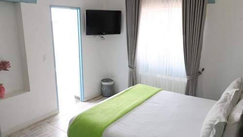 a bedroom with a bed with a green blanket at Casa Hotel Santa Helena Boutique in Villa de Leyva
