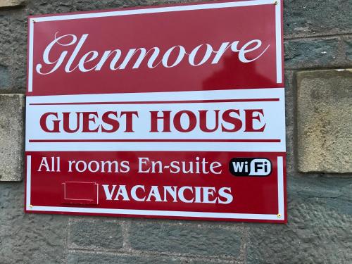 a sign for a guest house on a brick wall at Glenmoore Guest House in Oban