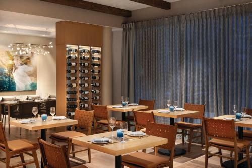 ein Restaurant mit Tischen, Stühlen und Weinregalen in der Unterkunft Seaside Hotel North Vancouver in North Vancouver