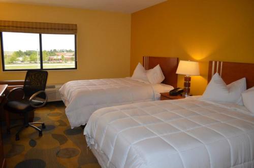 a hotel room with two beds and a desk and a window at Marble Waters Hotel & Suites, Trademark by Wyndham in Jacksonville