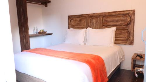 a bedroom with a white bed with a wooden headboard at Casa Hotel Santa Helena Boutique in Villa de Leyva