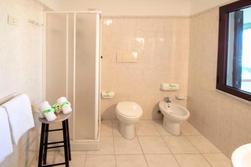 ein weißes Bad mit einem WC und einem Waschbecken in der Unterkunft Hotel Smeraldo in Isola Rossa