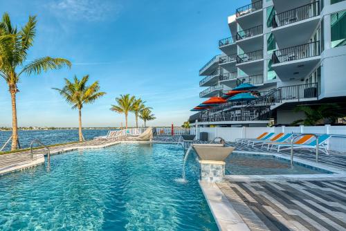 a swimming pool with palm trees and a building at FUSION Resort Two Bedroom Suites in St. Pete Beach