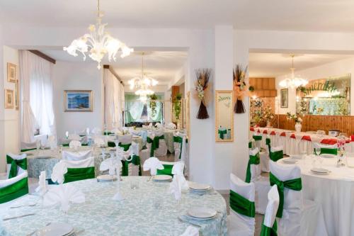 um salão de banquetes com mesas brancas e cadeiras verdes em Hotel Smeraldo em Isola Rossa