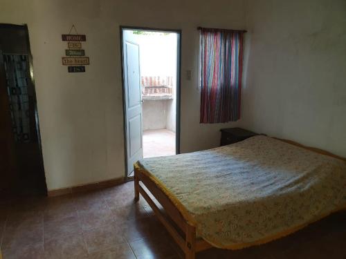 1 dormitorio con 1 cama y puerta a una ventana en Departamentos ramallo, en Ramallo