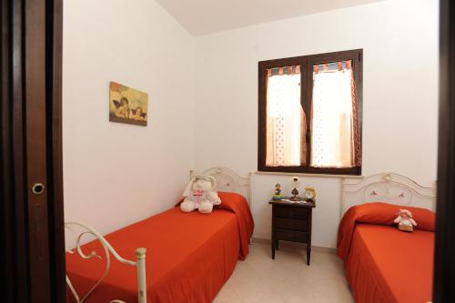 two beds in a bedroom with red sheets and a window at Carmelina in Marina di Pescoluse