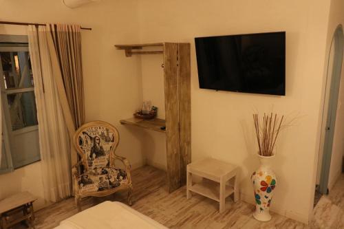 a living room with a chair and a television on the wall at Casa Hotel Santa Helena Boutique in Villa de Leyva