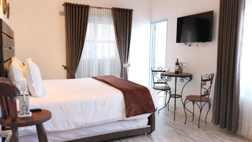 a bedroom with a bed and a table and a window at Casa Hotel Santa Helena Boutique in Villa de Leyva