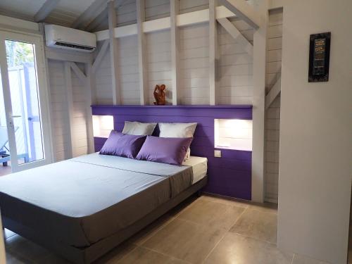 a bedroom with a bed with a purple headboard at Caraïbes Cottages Jellyfish piscine privée a 900m de la plage de Grande Anse in Deshaies
