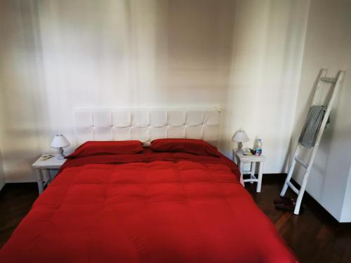 a bedroom with a red bed with two tables and a tv at La Sibilla in Macerata