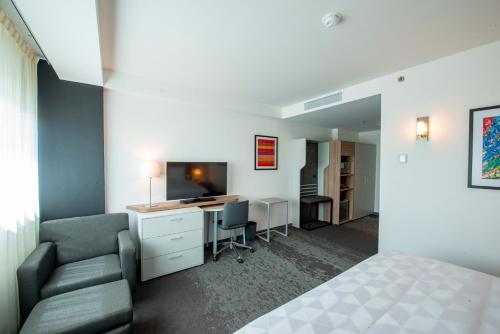 1 dormitorio con 1 cama y escritorio con TV en Holiday Inn & Suites - Merida La Isla, an IHG Hotel en Mérida