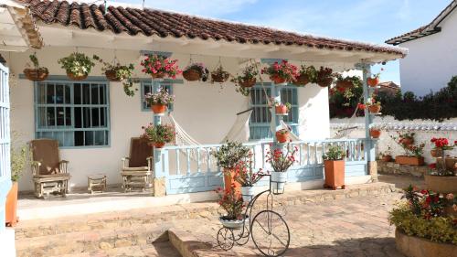 a white house with potted plants and a bike in front at Casa Hotel Santa Helena Boutique in Villa de Leyva