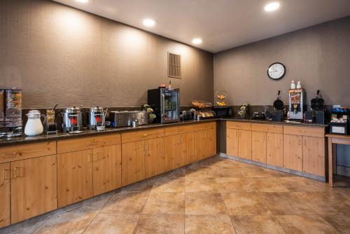 a kitchen with wooden cabinets and a clock on the wall at La Quinta by Wyndham Eugene in Eugene