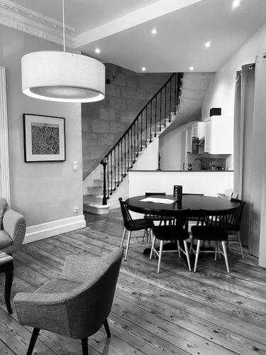 une salle à manger avec une table et des chaises et un escalier dans l'établissement Romance au coeur de Bordeaux / Jardin Public, à Bordeaux
