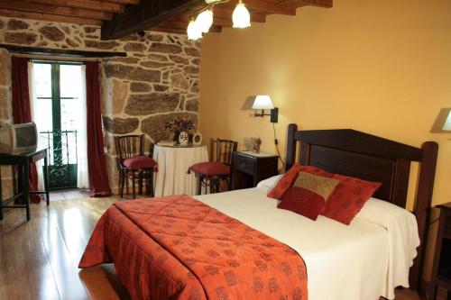 1 dormitorio con 1 cama y 1 mesa con sillas en Casa Rural Rectoral de Candás, en Rairiz de Veiga