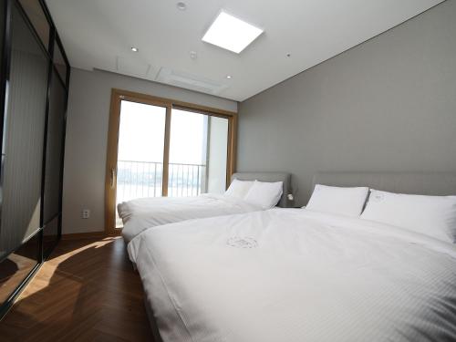 two white beds in a room with a window at 쏘타스위트 속초 월드스테이트 in Sokcho