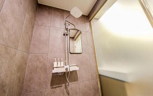 a shower stall in a bathroom with a mirror at Hotel OU in Busan