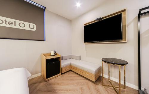 a room with a flat screen tv and a stool at Hotel OU in Busan