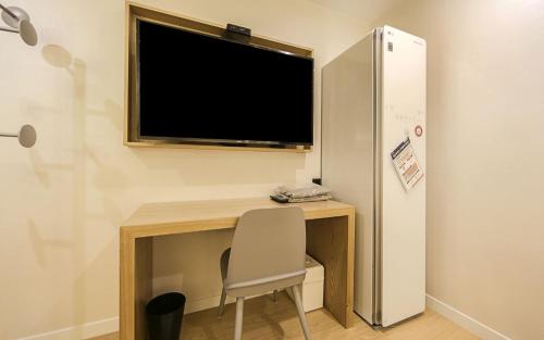 a desk with a television and a chair in a room at Hotel OU in Busan