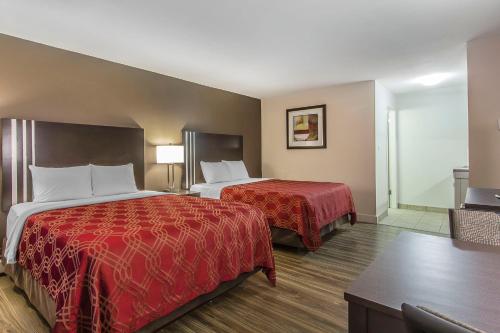 a hotel room with two beds with red sheets at Econo Lodge Inn & Suites in Lethbridge