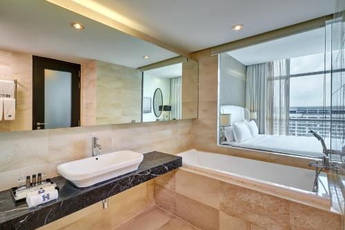 a bathroom with a tub and a sink and a mirror at Hatten Hotel Melaka in Melaka
