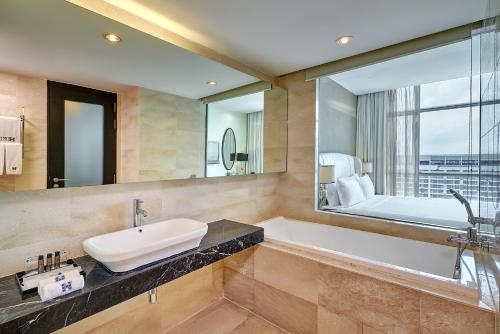 a bathroom with a tub and a sink and a mirror at Hatten Hotel Melaka in Melaka