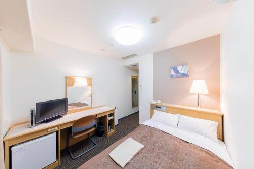 a hotel room with a bed and a desk at Sunny Stone Hotel in Osaka