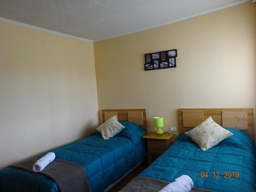 two beds in a room with blue sheets at Cabañas Troncos de Alerce en Puerto Montt con tinaja caliente in Alerce