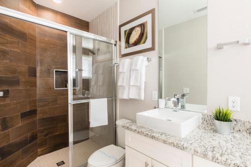 La salle de bains blanche est pourvue d'un lavabo et d'une douche. dans l'établissement 4 BR 4 BA Luxury Villa 5min to Disneyworld 1804ft² free Gym, à Orlando