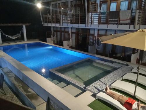 a swimming pool at night with a person laying on chairs and an umbrella at Ananda Resort in Panglao