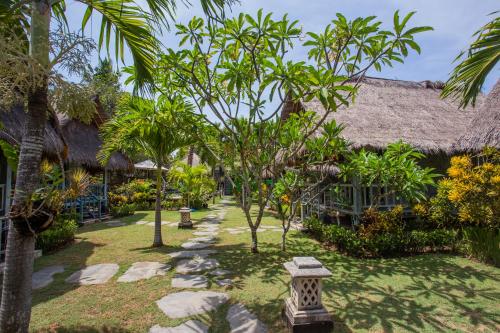 a garden in a resort with trees and rocks at TS Hut Lembongan in Nusa Lembongan