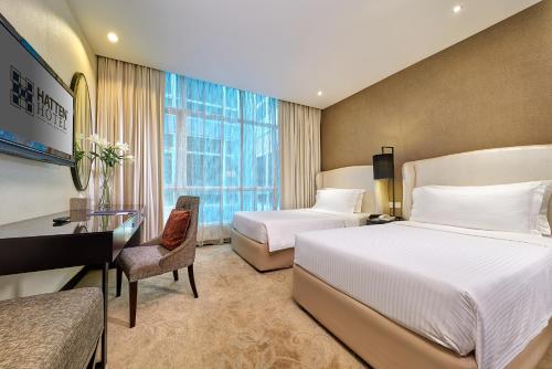 a hotel room with two beds and a desk at Hatten Hotel Melaka in Melaka
