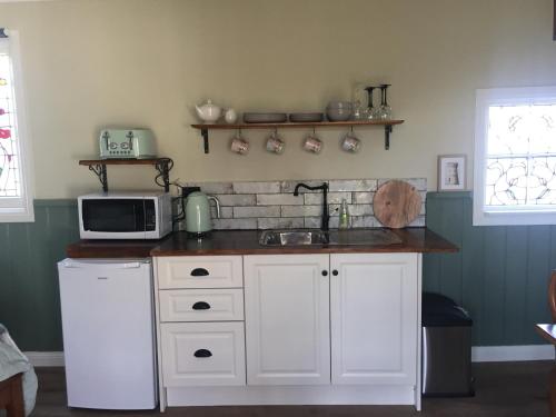 cocina con fregadero y microondas en Peg Cottage, en Evandale