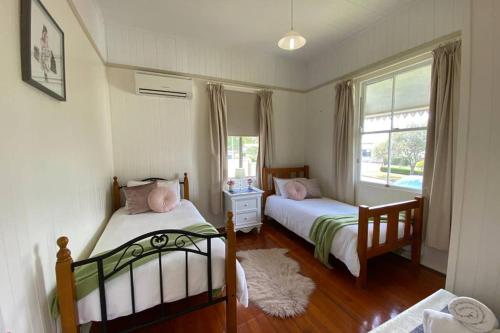 a bedroom with two beds and a window at Ashbrooke Cottage in Toowoomba