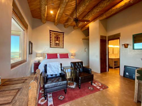 a bedroom with a bed and two chairs in a room at The Grand Hacienda Estate with Breakfast in Abiquiu