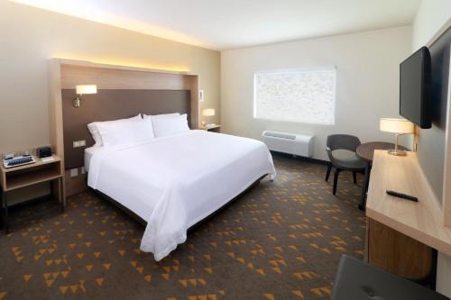 a hotel room with a white bed and a flat screen tv at Holiday Inn - Ciudad Juarez by IHG in Ciudad Juárez