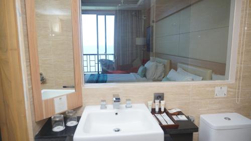 a bathroom with a white sink and a mirror at Sotis Hotel Kupang in Kupang