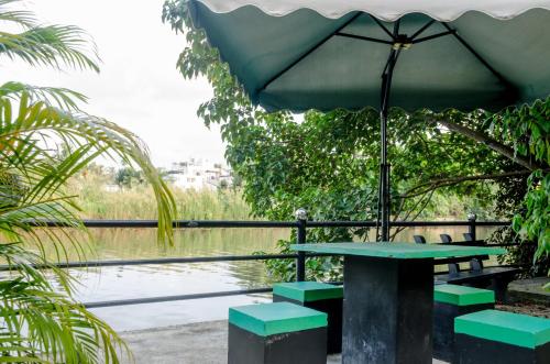 a picnic table with an umbrella next to a body of water at Opulent River Face Hotel in Colombo
