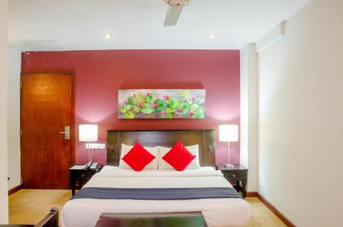a bedroom with a large bed with red pillows at Opulent River Face Hotel in Colombo