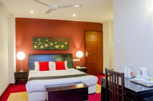 a bedroom with a large bed with red walls at Opulent River Face Hotel in Colombo