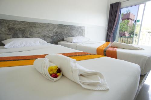 um quarto com três camas com lençóis brancos em แกรนด์ ฟอเรสท์ Grand Forest em Chanthaburi