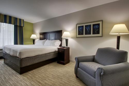 a hotel room with a bed and a chair at Holiday Inn Express Hotel & Suites Middleboro Raynham by IHG in Middleboro