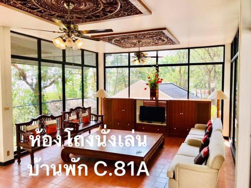 salon z kanapą, telewizorem i oknami w obiekcie Baan Rug Nam Sai w mieście Klaeng