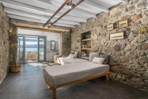 a bedroom with two beds and a stone wall at Capetan Nikolas-boat house in Klima