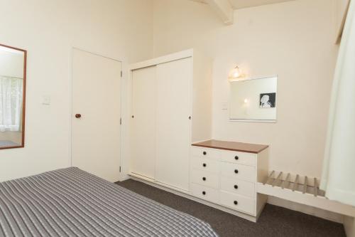 a white bedroom with a bed and a dresser at Kerikeri Court Motel in Kerikeri