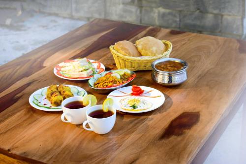 馬西歐博拉的住宿－Zostel Homes Mashobra (Shimla)，餐桌,盘子上放着食物和咖啡