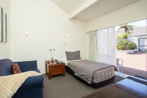 a bedroom with a bed and a table and a window at Kerikeri Court Motel in Kerikeri