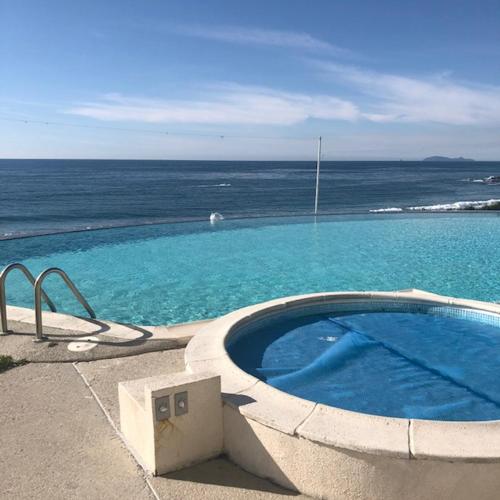a swimming pool with the ocean in the background at MODERN SPACIOUS BEACH FRONT CENTRAL CONDO w POOLS STEPS TO BEACH in Rosarito