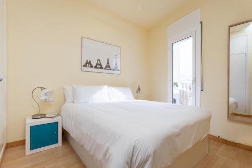 Un dormitorio con una gran cama blanca y una ventana en Penthouse Camp Nou, en Barcelona